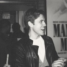 black and white photograph of a young man laughing at something in front of the camera