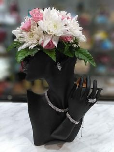 a black mannequin head with flowers on it's face and hands in the foreground