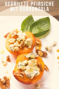 two stuffed oranges on a white plate with nuts and spinach leaves in the background