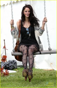 a woman sitting on a swing with her legs crossed and wearing fishnet tights