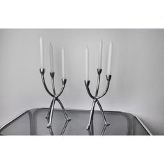 two candles are placed on top of each other in front of a metal tray with silver handles