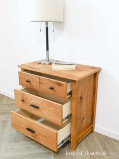 a wooden dresser with three drawers and a lamp on top