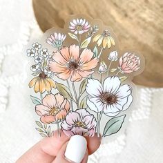 a hand holding a sticker with flowers on it