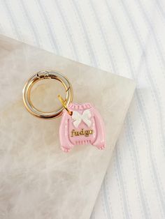 a pink keychain with a horse on it sitting on top of a piece of paper