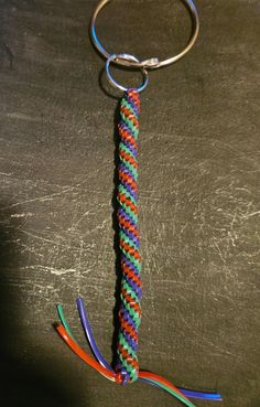 a multicolored rope keychain is hanging on a black surface with a metal ring