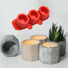 three cement planters sitting next to each other near a succulent and candle holder