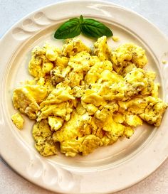 a white plate topped with scrambled eggs and basil