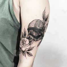 a man's arm with a helmet and flowers on it