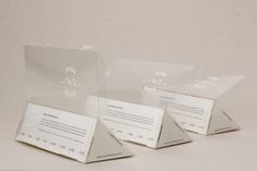 three clear acrylic business cards sitting next to each other on a white surface