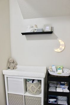 a baby's nursery room with white walls and black shelves