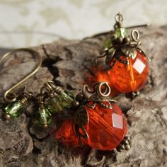 "A new twist to my original designthese adorable little pumpkins in spicy orange, faceted glass beads, dangle from a sparkly vine of tiny glass beads in peridot green. Still crowned in layers of antiqued brass leaves and curlycues vines these little pumpkins are perfect for that person wanting just a little bit more spice! Length from bottom loop of french earwire: 1.5\"(33mm) Prefer a different style of earwires? Non pierced clips as well as leverbacks are also available for no extra charge. Pl Vine Earrings, Pumpkin Vine, Peridot Green, Pumpkin Earrings, Orange Pumpkin, Pretty Box, Pumpkin Orange, Faceted Glass, Different Styles