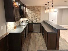 a kitchen with wooden cabinets and black counter tops in an empty room that has wood flooring