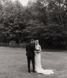 a bride and groom standing in the middle of a field with trees in the background