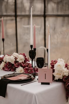 the table is set with black and white plates, pink napkins, and candles