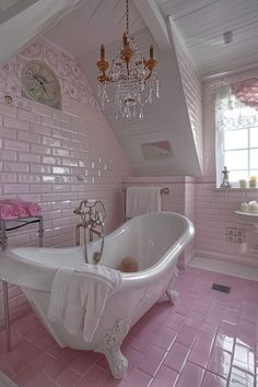 a pink bathroom with a claw foot tub and chandelier hanging from the ceiling