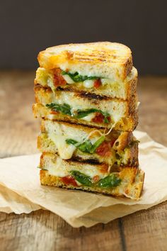 a grilled cheese sandwich stacked on top of each other with green peppers and tomatoes