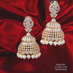 a pair of gold and white earrings on a red velvet background with the word shadurs written below it