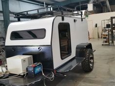 an off - road camper trailer is parked in a garage with its doors open