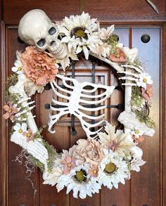 a wreath decorated with flowers and a skeleton on the front door for halloween or day of the dead