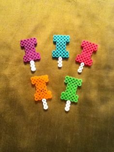 four small teddy bears made out of perler beads on a brown tablecloth with white buttons