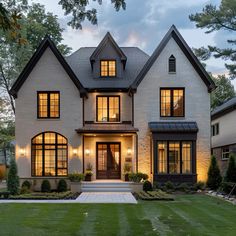 a large white brick house with lots of windows and lights on it's front