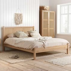 a bed sitting in a bedroom next to a wooden dresser and window on top of a hard wood floor