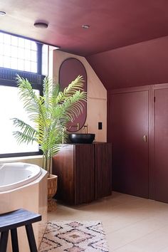 a bath tub sitting next to a wooden cabinet in a room with purple walls and flooring