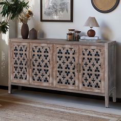 a sideboard with an intricate design on the doors and drawers in a living room