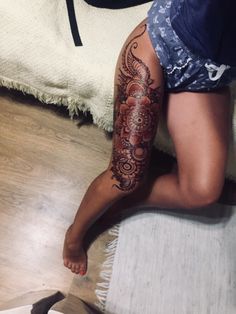 a woman's legs with tattoos on them sitting on the floor next to a bed