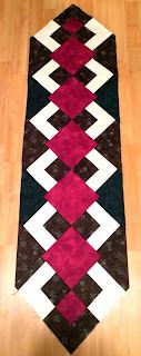 a black, white and red rug on the floor with wood floors in the background