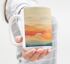 a woman holding a coffee mug with an abstract painting on the front and sides of it