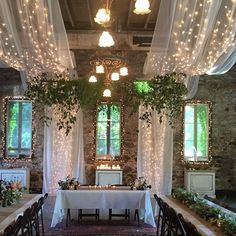 an indoor dining area with tables and chairs covered in white cloths, surrounded by greenery