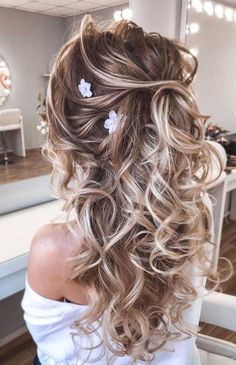 the back of a woman's head with curly hair and flowers in her hair