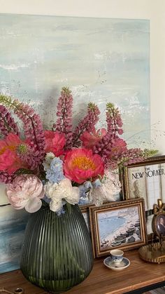 a vase filled with pink and white flowers on top of a table next to pictures