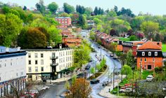 an aerial view of a small town with lots of trees on the hill behind it