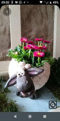 a ceramic sheep planter with pink flowers in it