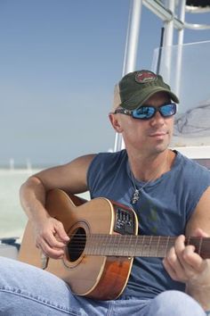 a man sitting on a boat playing a guitar