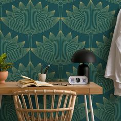 a desk with a lamp, book and plant on it next to a wallpaper