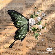 a green and black butterfly sitting on top of a piece of paper next to flowers