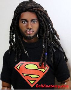 a man with dreadlocks wearing a superman t - shirt and standing in front of a white wall