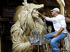 a man sitting on a stool next to a statue