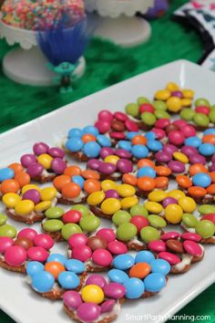 there are many colorful candy candies on the white plate and green tablecloths