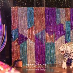 a white tiger standing on top of a stage covered in purple and green streamers