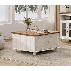 a living room with a coffee table and white furniture in the corner on carpeted flooring