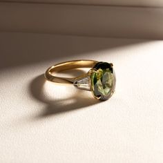 an oval shaped green and white ring with two pears on the side, set in yellow gold