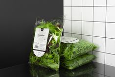 two bags of lettuce sitting on top of a counter next to each other