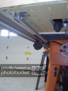 the inside of a garage with tools hanging from it's ceiling and an orange work bench underneath