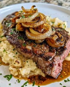 steak with onions and mashed potatoes on a plate