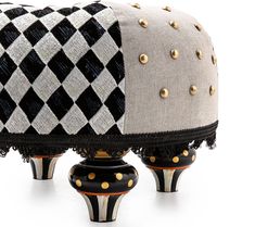 two black and white vases with gold studded accents on them, one sitting on top of the other