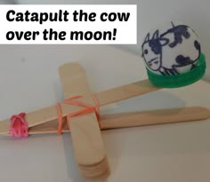 a wooden cross with a cow painted on it next to an egg in the shape of a toothpick